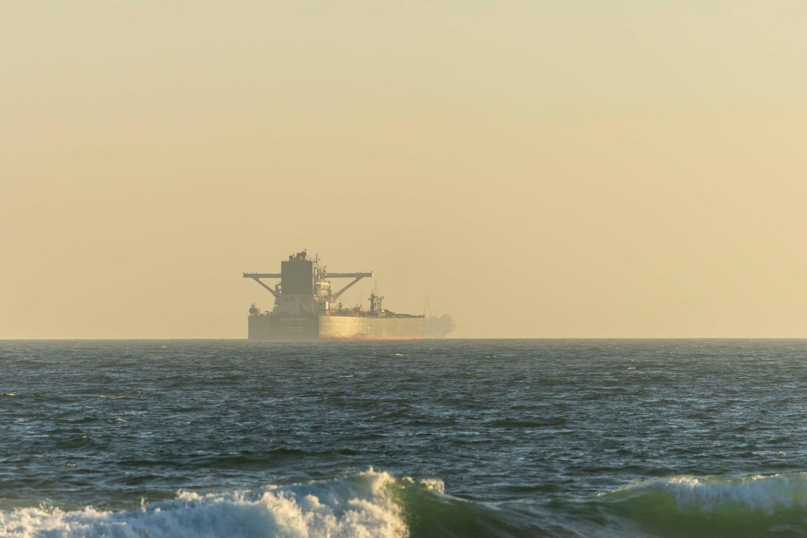 Vraquier à l'horizon sur une mer agitée, dans la lumière de fin de journée.